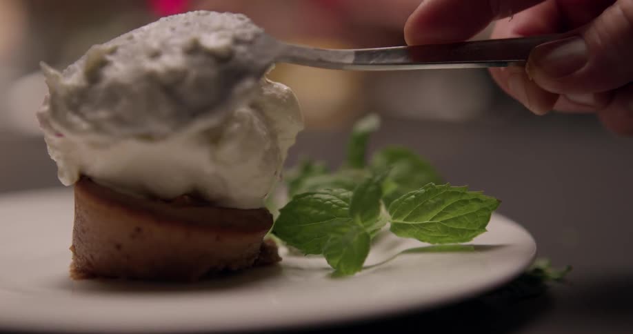 A chef places a dollop of a cream on top of food on a plate