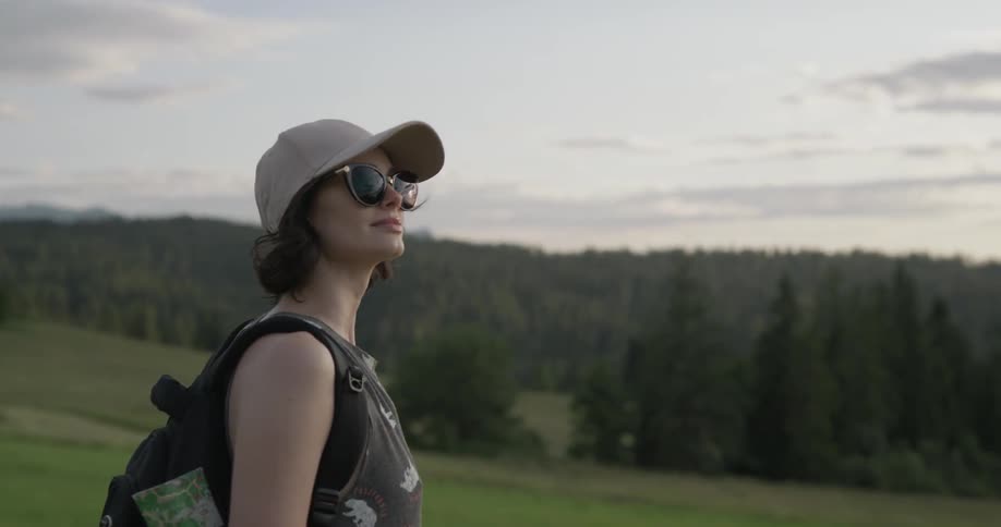 A woman stands in a clearing on a hill looking at the scenery