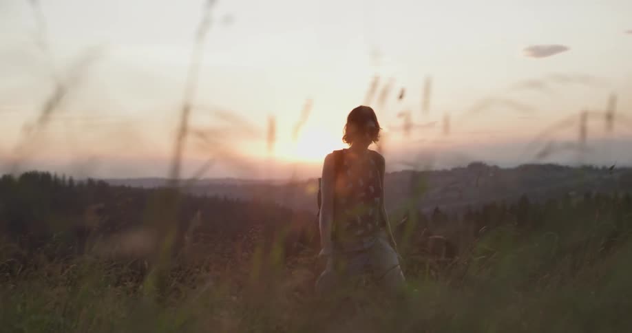 Woman hiking through a field at sunset