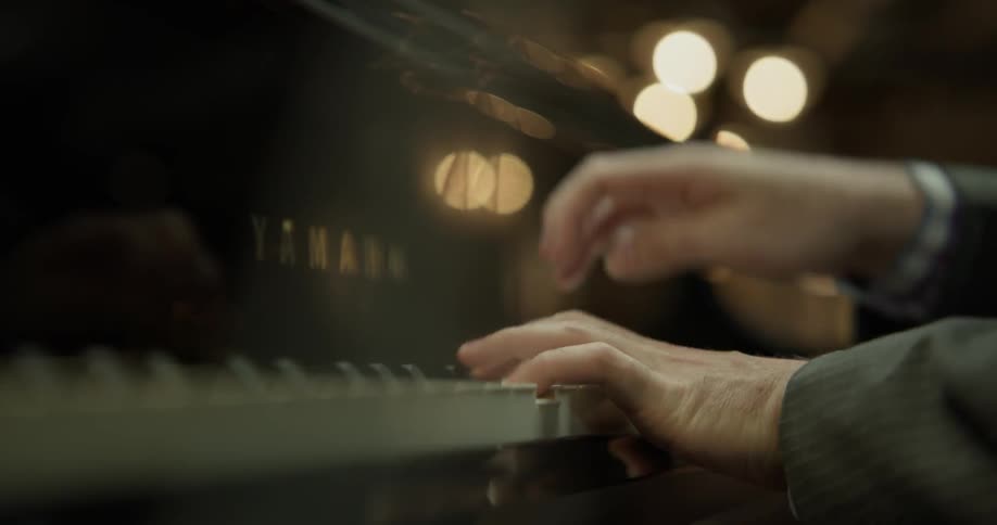 A man crosses his arms while playing the piano