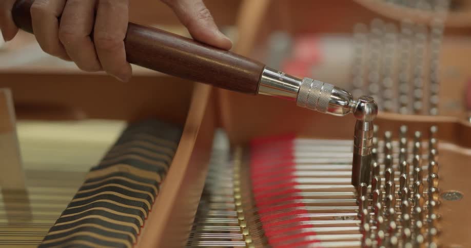 A man tunes a piano with specialty tools