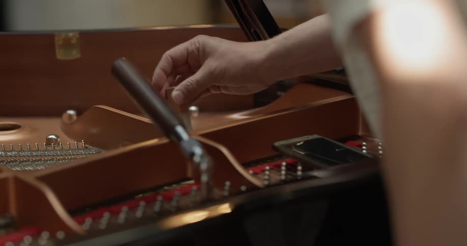 A piano tuner tunes a grand piano