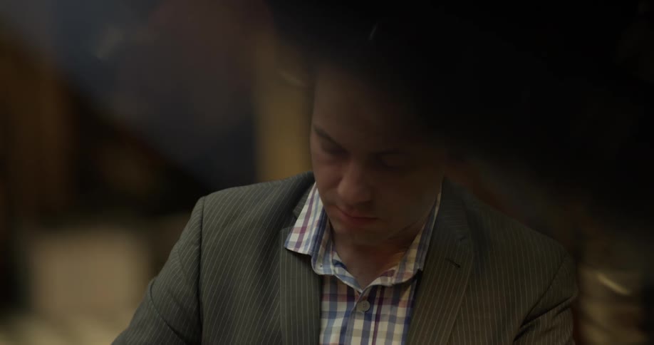 Bald headed man wearing shirt and blazer concentrates on playing the piano indoors at night