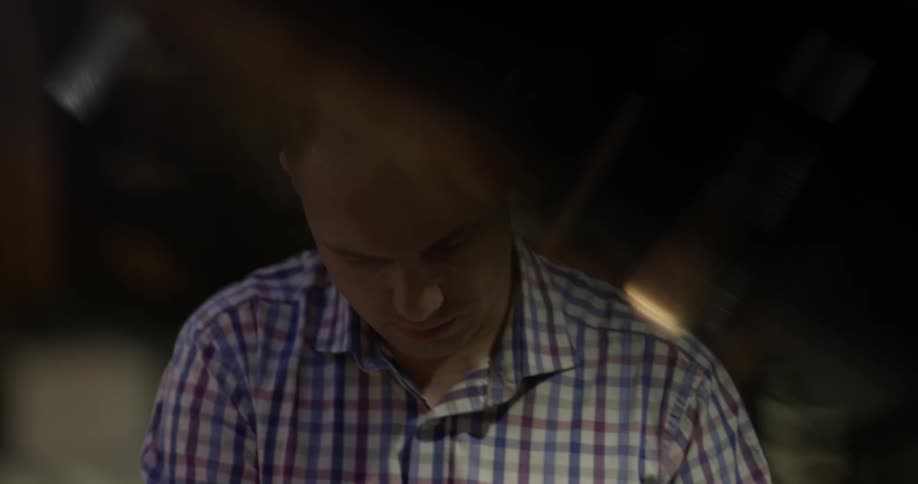 Man wearing striped shirt plays the piano indoors at night