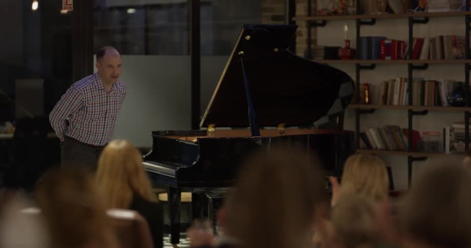 A male pianist takes the applause of a room of people