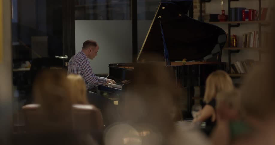 Man playing piano in front of a small audience