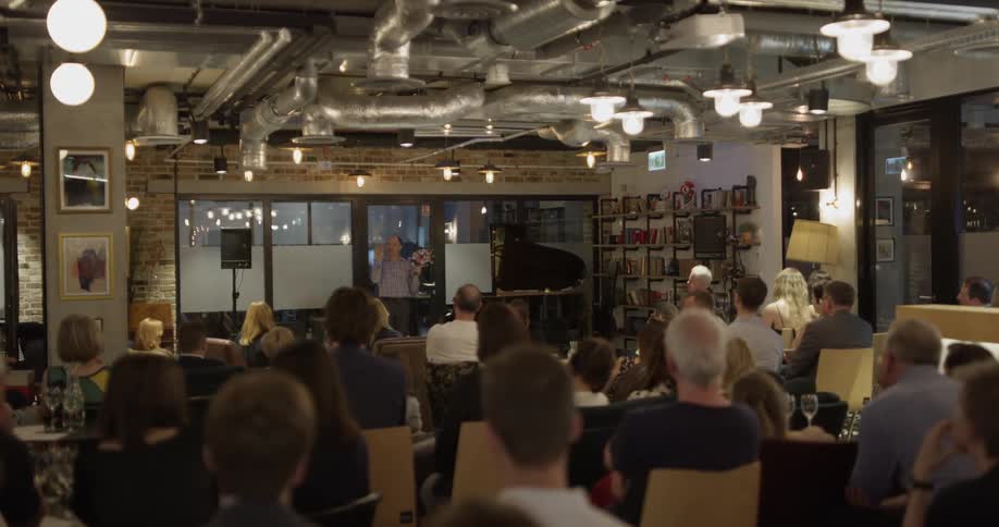A man with flowers in his hands talking to an audience