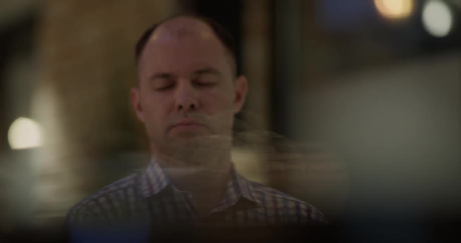Bald headed man plays the piano indoors at night
