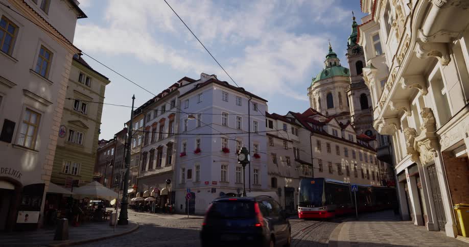 A trolley travels on the narrow street of an old city on a sunny day