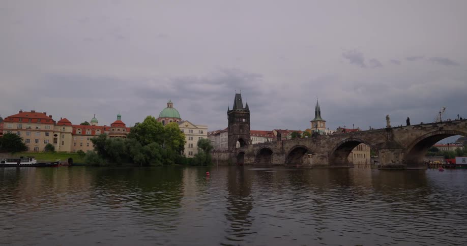 Small waves ripple on the surface of a river as it flows under a bridge next to a city