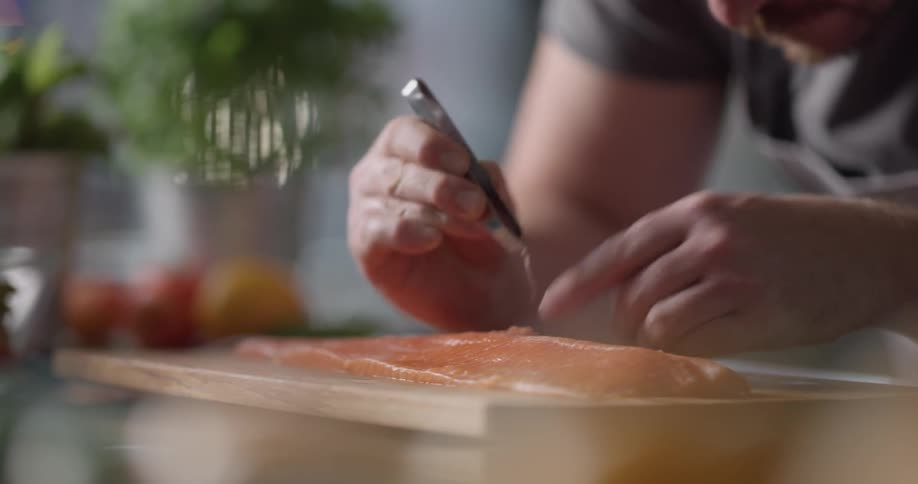 Chef carefully removing spines of a salmon slice