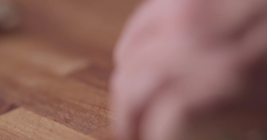 A chef slices a pepper in half on a butcher block cutting board