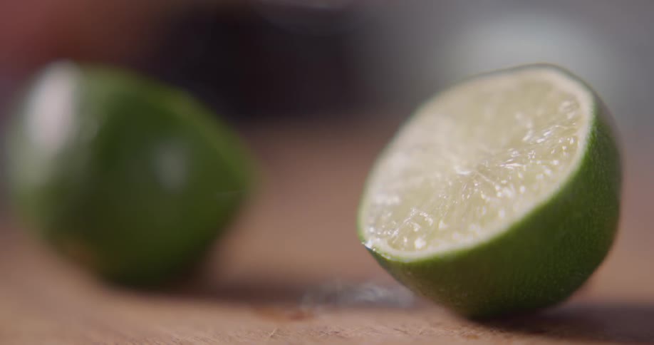A cut lime is picked up from a cutting board