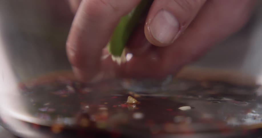 A hand squeezes lime juice into a sauce