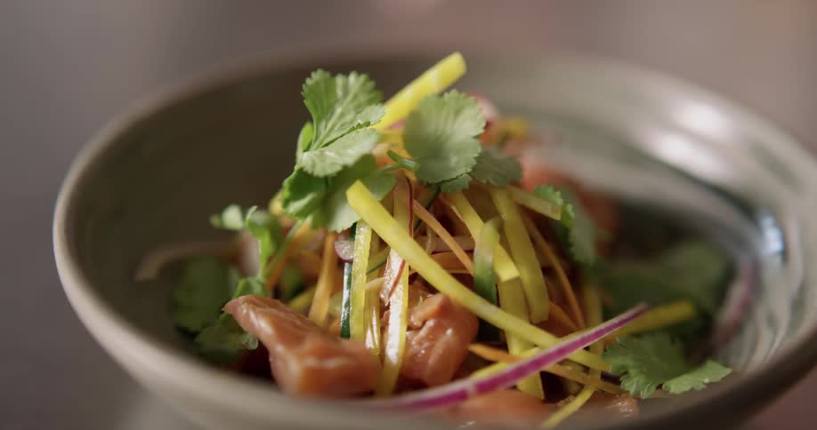 Salad in the mini bowl is being put on the table during daylight