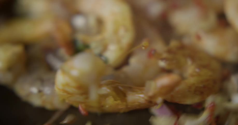 Shrimp and spices being tossed in a skillet