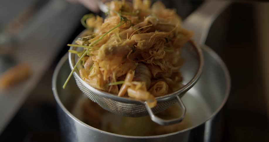 A person pours food into a strainer