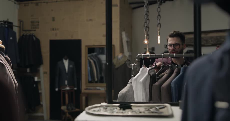 Man picks suit pants from store display rack