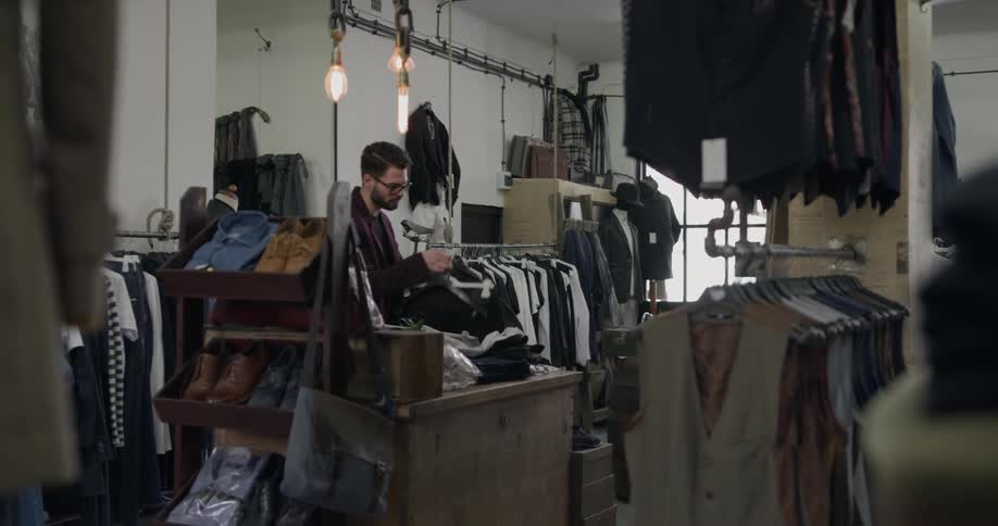 A man taking clothing from a counter in a men's clothing store