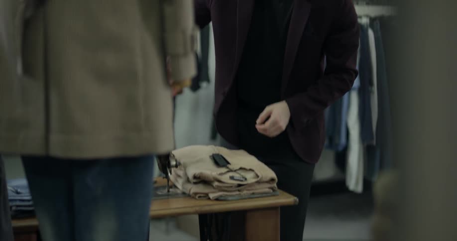 A man in a clothing store folding sweaters