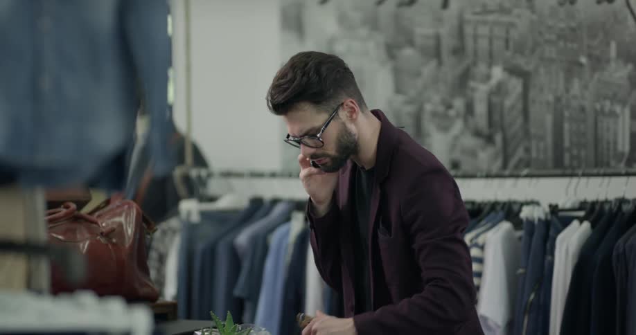 A man straightening clothes and talking on the phone
