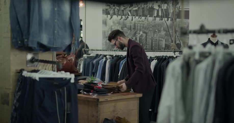 Man folds trousers in suit shop