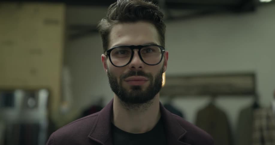 A man in a clothing shop raising his head to look at the camera