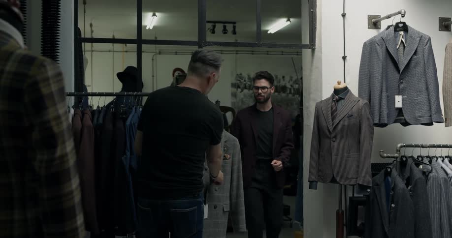 A man showing an employee about clothes on a rack