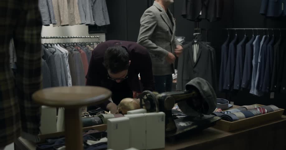 A clothing shop worker helping fit a man in a suit jacket