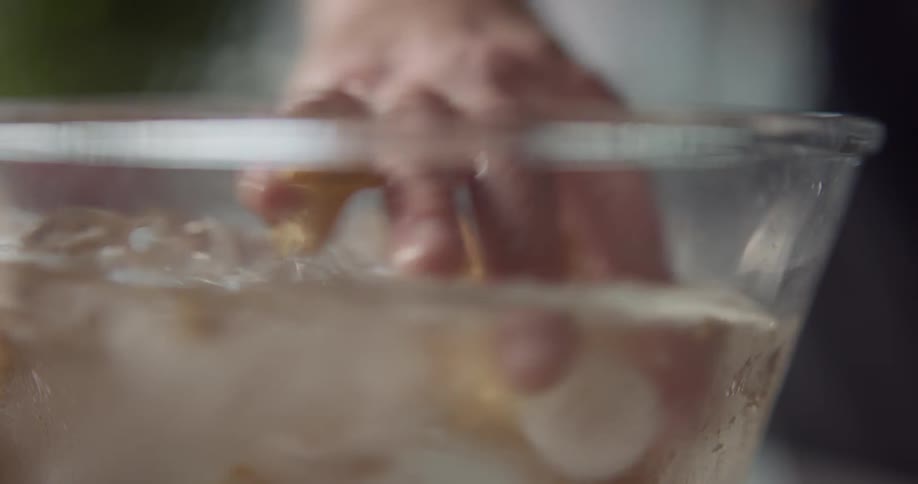 A hand stirs food in an ice bath