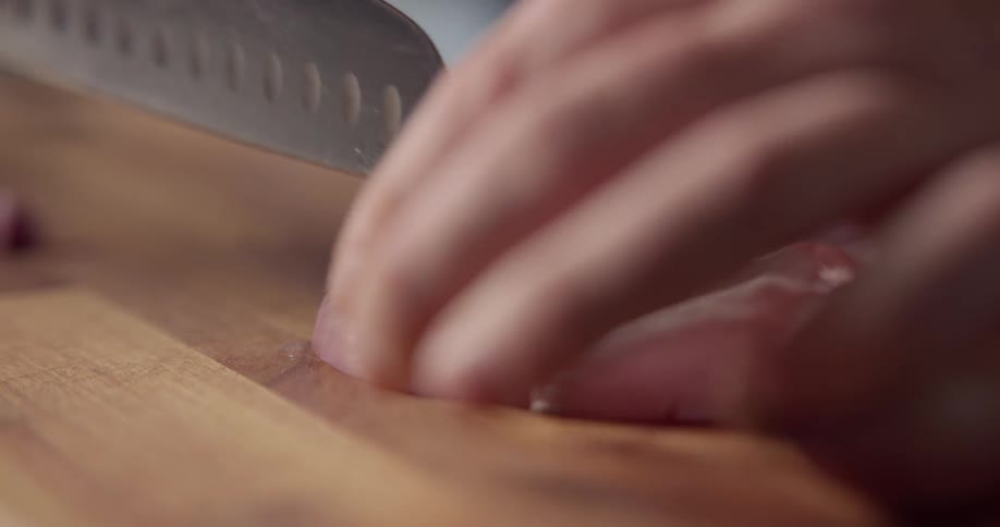 Chef slicing garlic with a knife on a cutting table