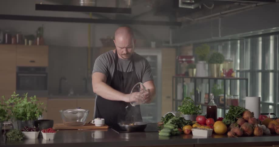 A man throws food into a hot skillet