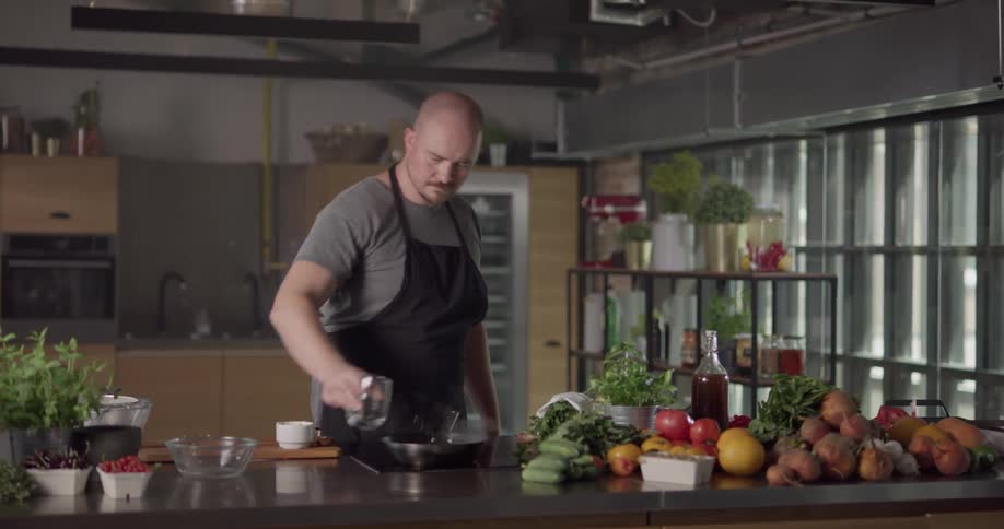 A chef is pouring ingredients in a pan