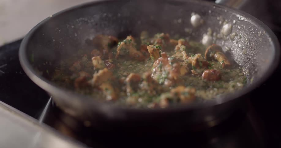 Mushrooms sizzling in a broth on a black skillet
