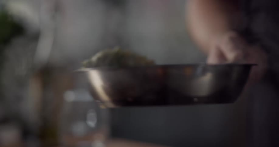 A person shakes a saute pan to toss the ingredients