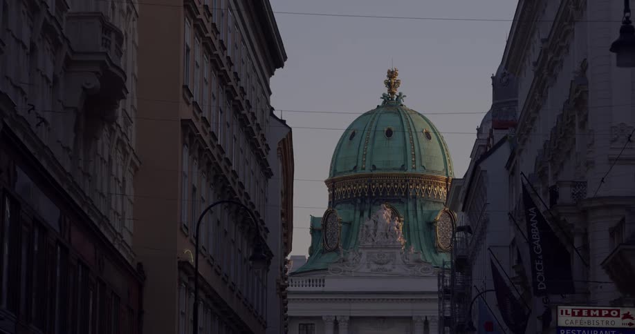 An ornate and expertly crafted dome sits atop a building that is located in an urban locale surrounded by several other buildings
