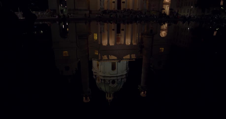 The reflection of a basilica on a body of water at night