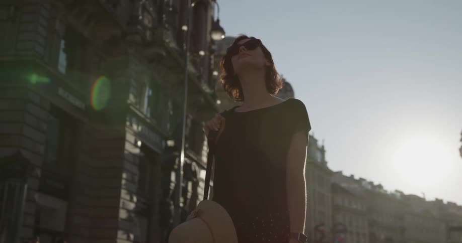 A woman is standing in the busy city street looking up
