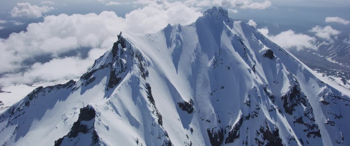 Snowy mountains are surrounded by clouds