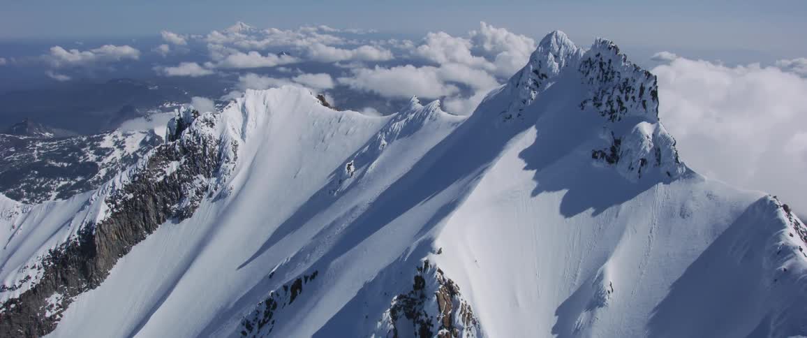An aerial view of a snowy mountain ridge on a cloudy day