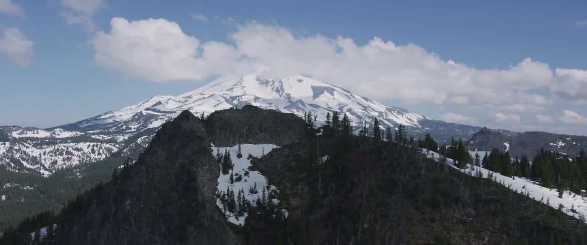Clouds surround a snowy mountain peak