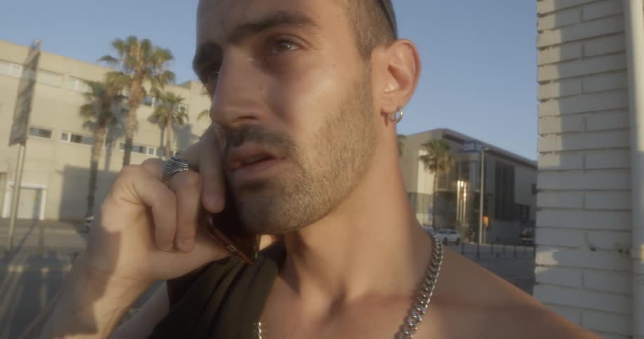 Man stands outside building talking on cell phone