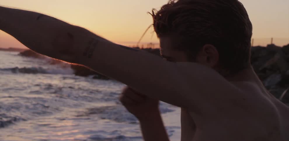 A young man shadow boxes on the beach