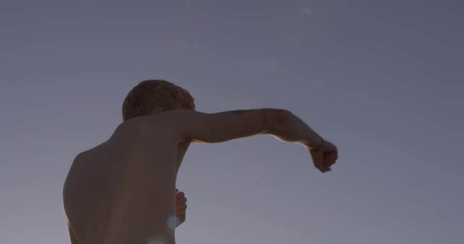 Shirtless man practices combat moves
