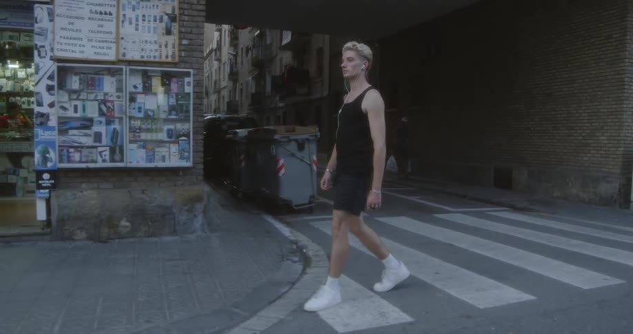 A man crosses a crosswalk next to a shop