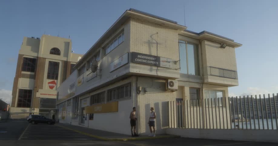 Two men are standing at the edge of the building talking and recreating a fight moves