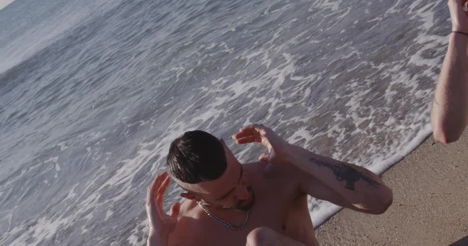 Two males do press ups on the beach in daylight