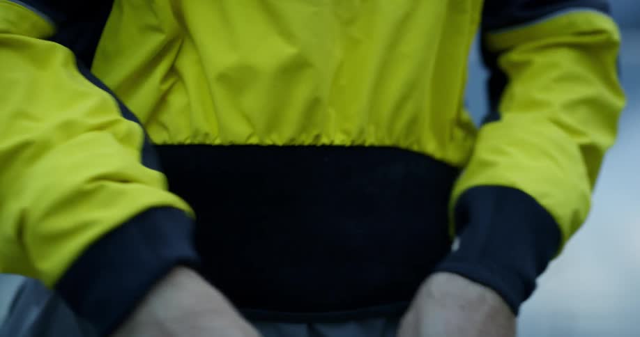 Man puts on yellow coat at dusk