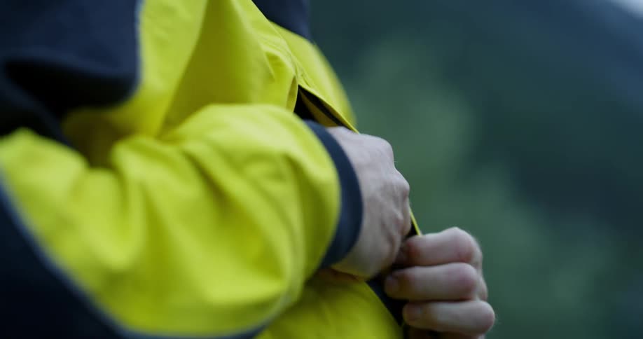 A person unzips a jacket pocket sticks a hand in the pocket and then closes the zipper