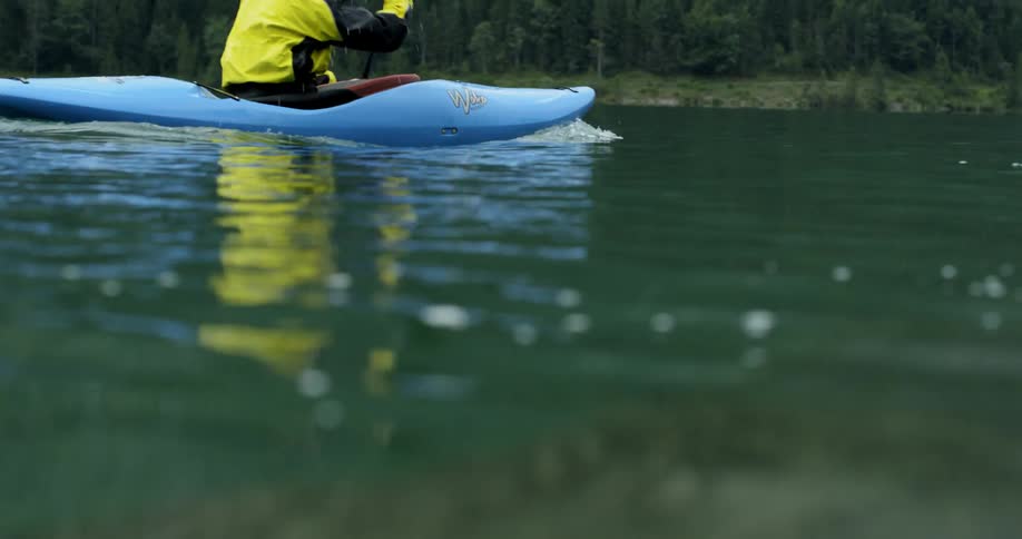 A caucasian male is kayaking down a body of water